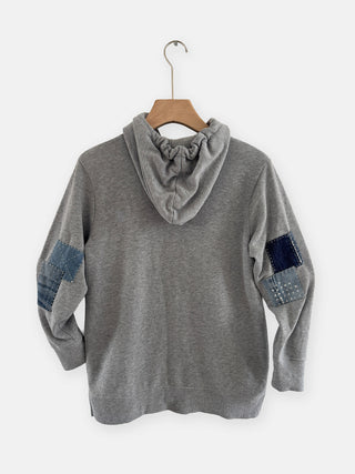 Gray hoodie with denim patch details on a white background