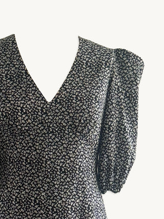 Sustainable black floral dress with ruffled sleeves on a white background