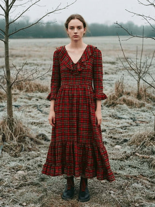 Woman in a red plaid dress standing in a foggy, landscape.
