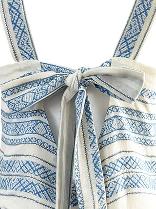 Close-up of a white dress with blue patterns and bow on a white background