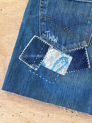 Close-up of a blue denim patch with white text on a wooden surface