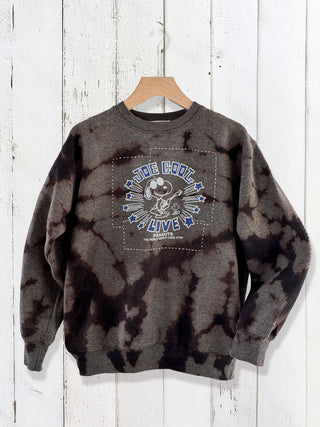 Tie-dye sweatshirt with graphic design on a wooden hanger against a white wooden panel background