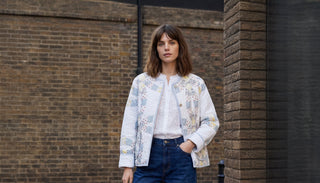 women in patchwork jacket outdoors by brick wall