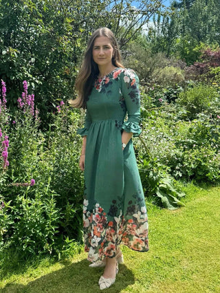 Woman in a green floral dress standing in a garden