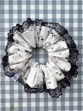 Decorative lace scrunchie with floral patterns on a checkered fabric background