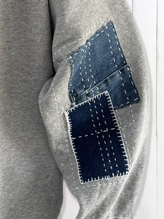 Gray sweatshirt with denim patches on a white background